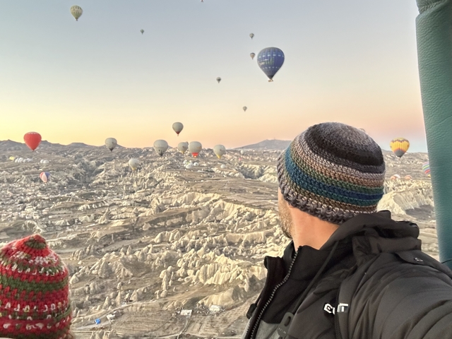       Person looking out from a hot air balloon over rocky terrain
  