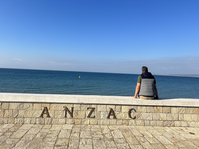       Person sitting by ANZAC memorial with sea view
  