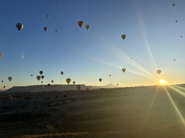       Hot air balloons at sunrise with a mountain in the distance
  