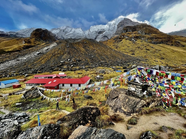       Prayer flags and buildings at the base of snow-capped mountains.
  