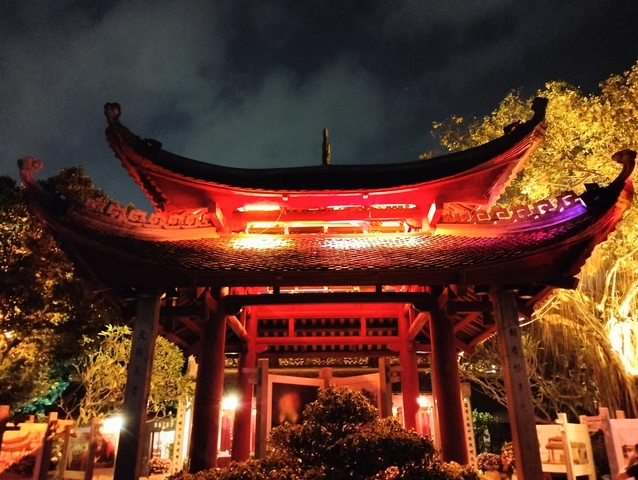       Illuminated traditional structure at night.
  