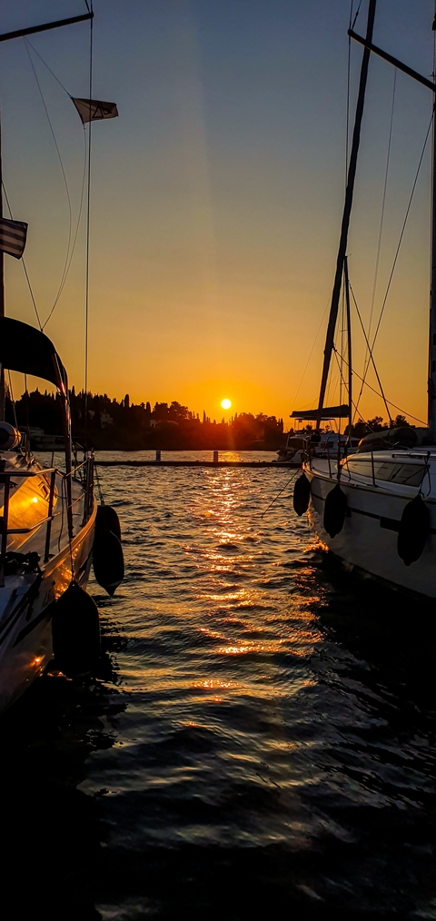 Sunset over the sea with silhouetted boats.