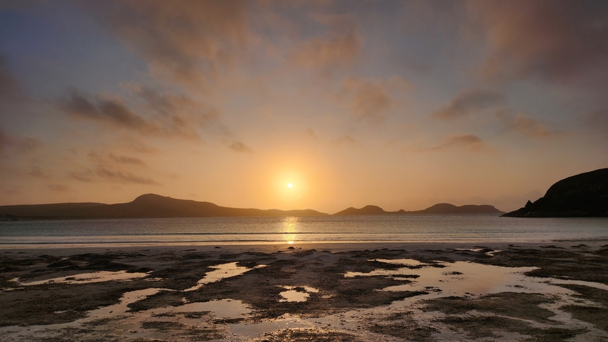 Sunset casting warm hues over a tranquil beach landscape.