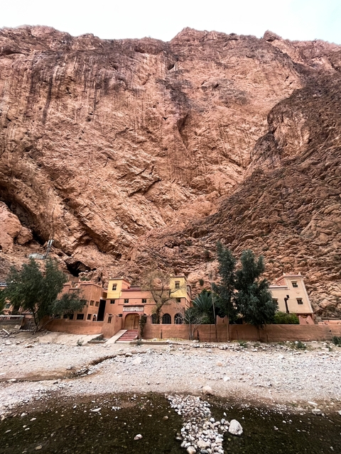 Buildings nestled against a massive rocky cliff.