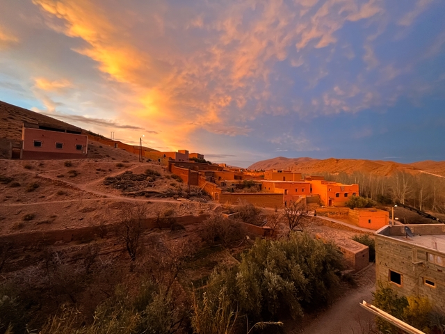 Scenic village with orange buildings under a colorful sky.