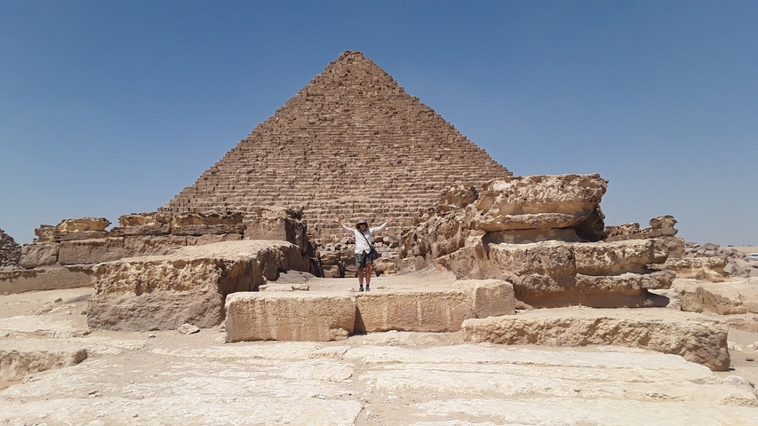       Person standing in front of an ancient pyramid.
  