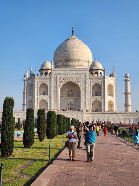 Tourists taking photos in front of a large white monument.