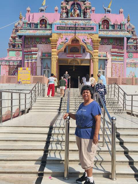 Person posing in front of a colorful temple entrance.