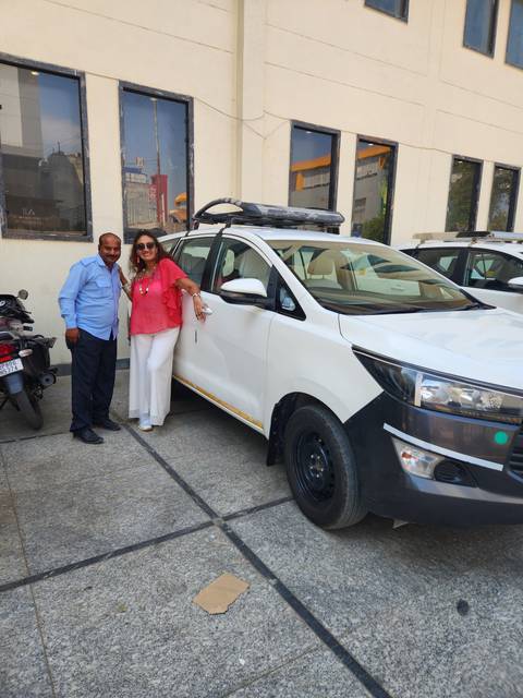 Two people standing next to a white vehicle.