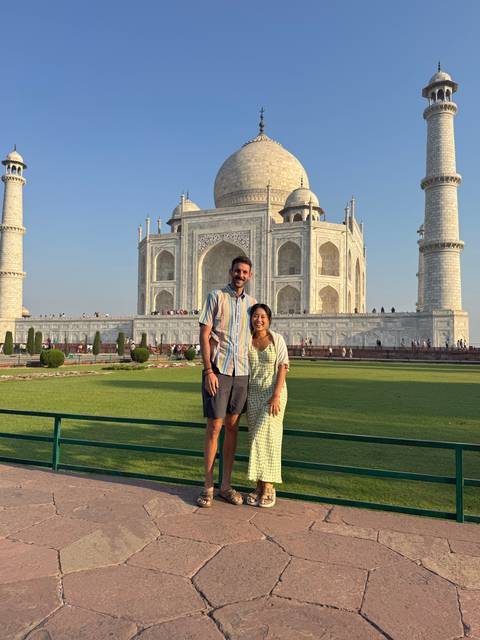 Two people standing in front of the Taj Mahal.