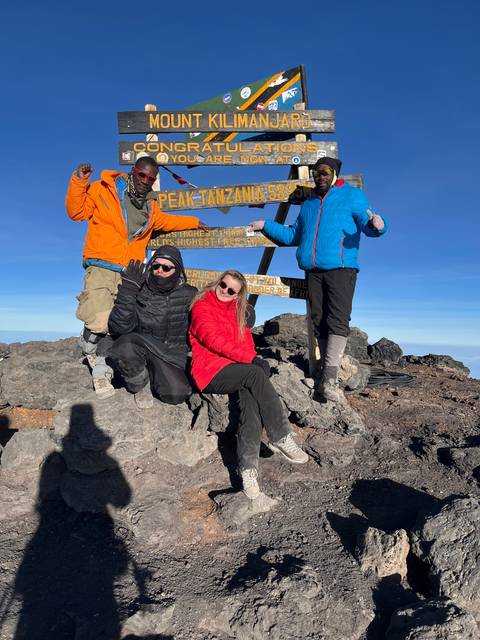Group at Mount Kilimanjaro summit sign.