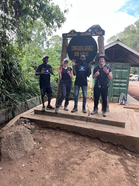 Group photo at Kilimanjaro National Park entrance sign.