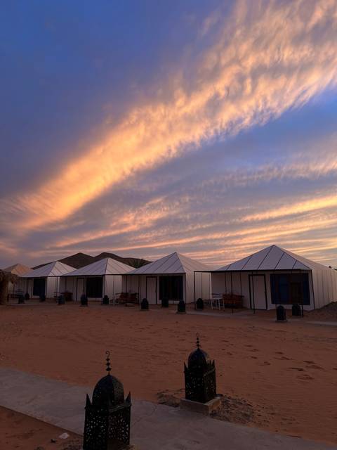 Tent camp with lanterns under a beautiful sunset.