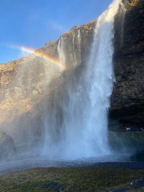 Waterfall with rainbow and onlookers below.