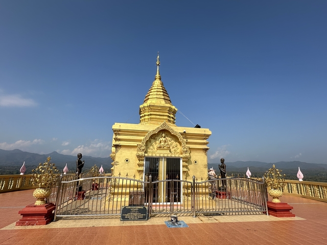       Golden temple with statues and clear blue skies.
  