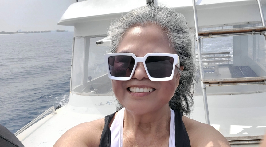       Person smiling on a boat with sea in background.
  