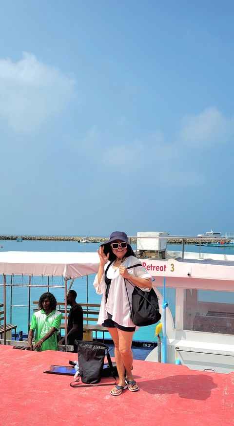       Person posing on a boat with ocean backdrop.
  