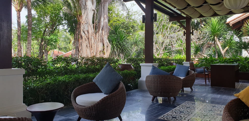 Outdoor seating area with wicker chairs and lush tropical surroundings.