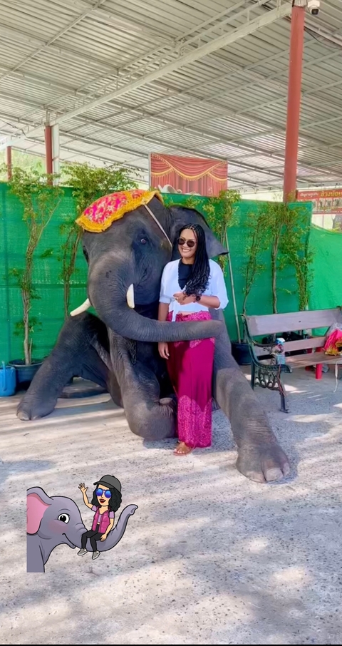 Person posing with an elephant in an outdoor setting.