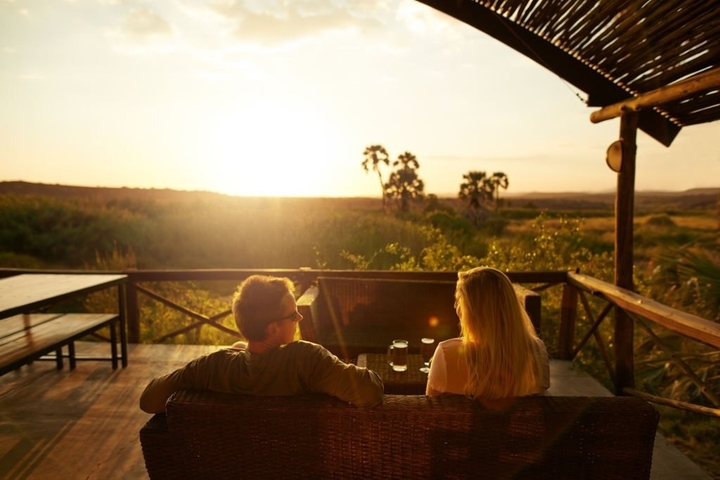       Couple relaxing while watching a sunset over the landscape.
  