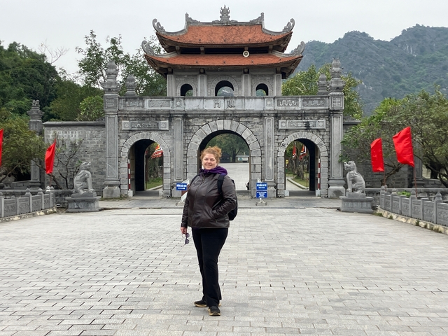       Person standing in front of a traditional Vietnamese gate.
  