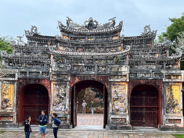 Group of tourists in front of an ornate historical gate.