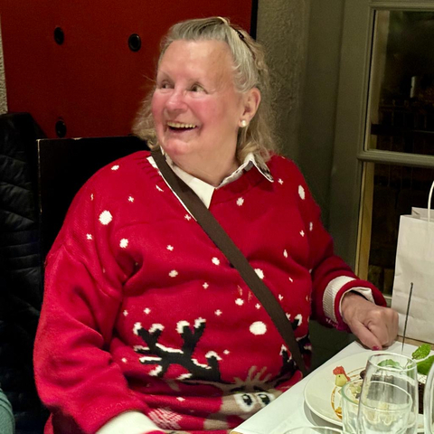       Elderly woman smiling while dining.
  