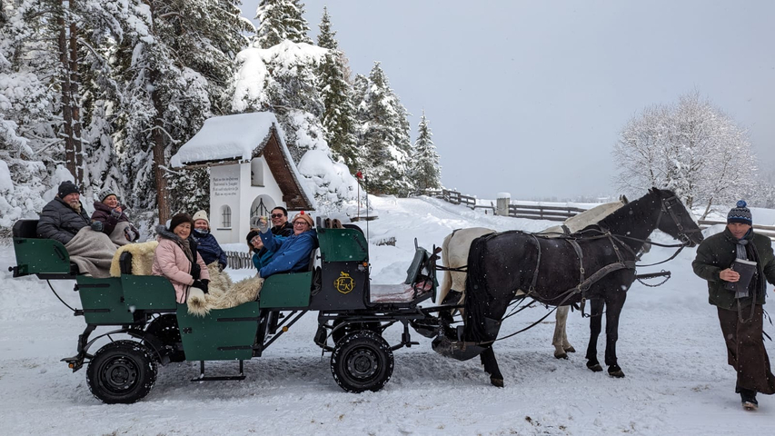 Happy group posing on a horse-drawn sleigh in the snow.