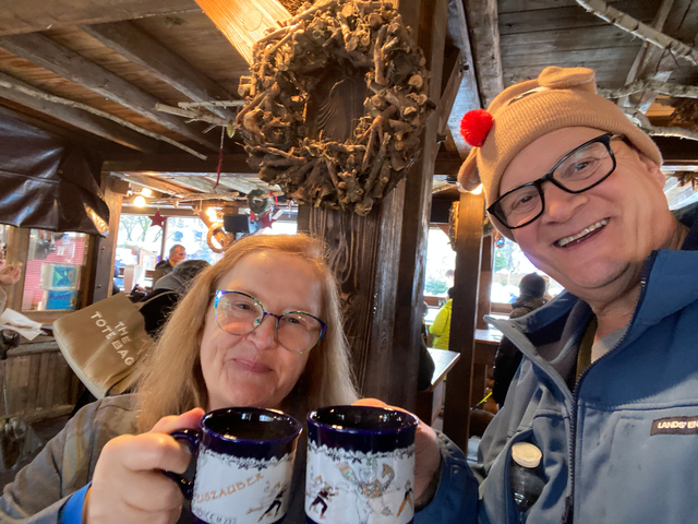 Couple enjoying hot drinks in a cozy wooden cabin.