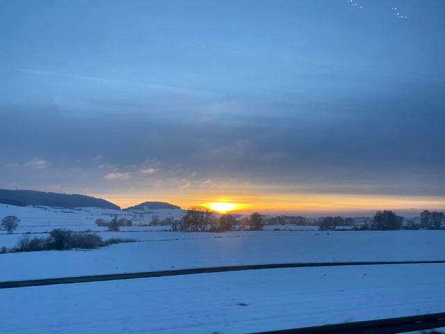       Snow-covered field with a sunset in the background.
  