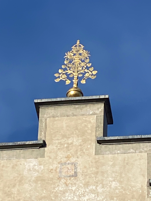       Golden ornament atop a tall stone pillar against a blue sky.
  