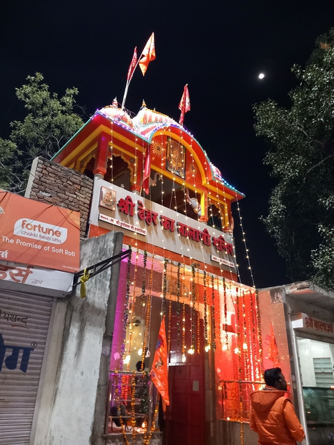 Illuminated temple at night with colorful lights.