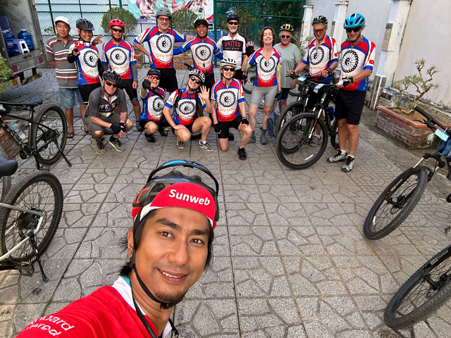 A group of cyclists posing for a photo, selfie style.