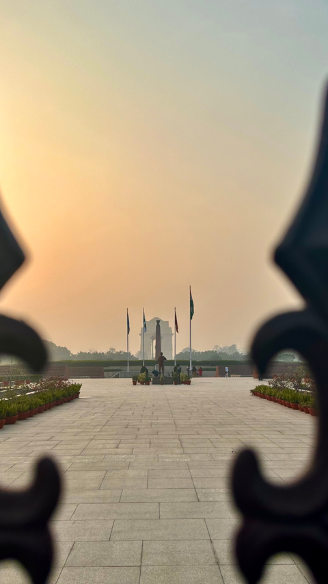       Silhouette of a monument with people and flags at sunrise.
  