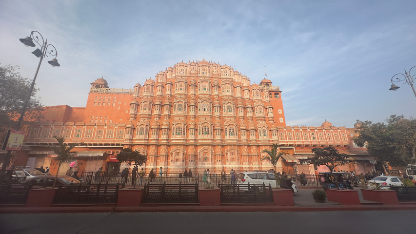       Hawa Mahal with people and vehicles on the street.
  