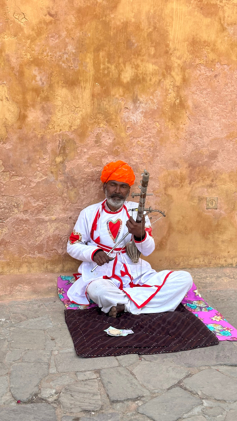       Man in traditional attire playing an instrument.
  