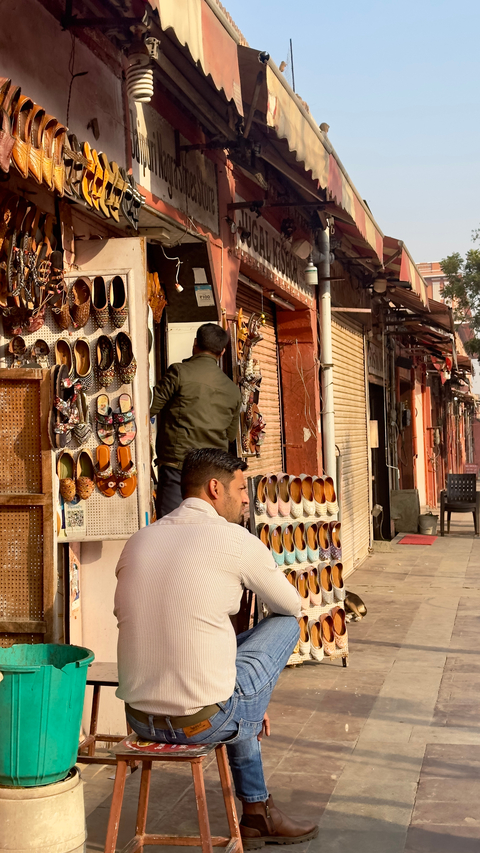       People browsing a shop street with traditional footwear.
  