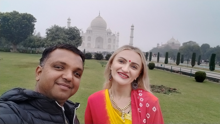 Two people smiling in front of the Taj Mahal.