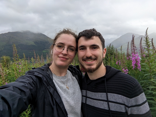 Couple posing with a mountainous landscape in the background.
