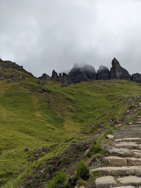 Rocky hillside with dark, cloud-covered peaks.