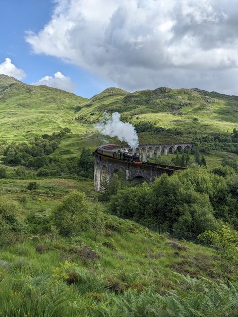 Steam train crossing a historic viaduct.
