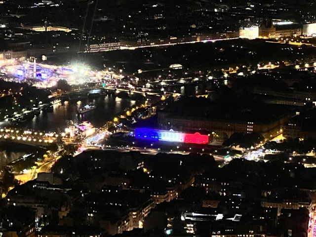       Night view of illuminated buildings and river in a city.
  