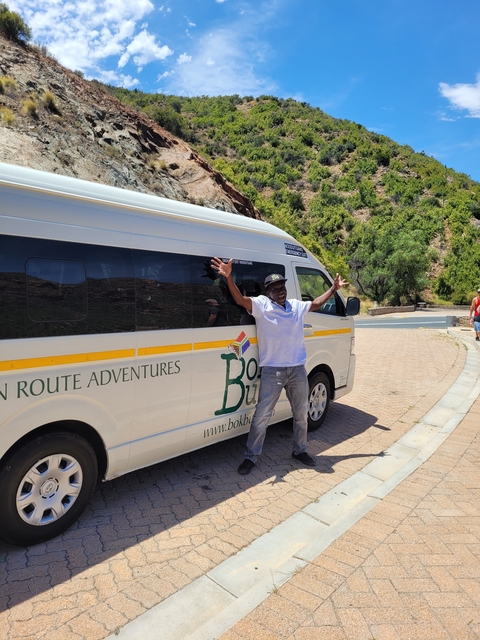 Man posing with arms wide in front of a van.
