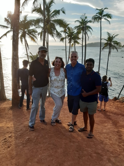 Group of people standing beside the ocean as the sun sets.