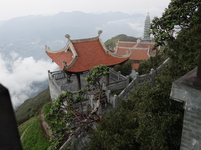 Traditional temple structure on a mountain with clouds.