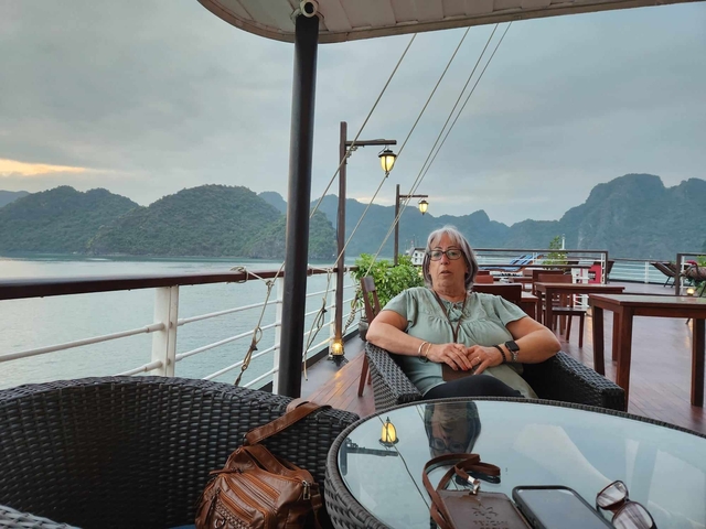 Person sitting on a deck of a boat with a view of Halong Bay.