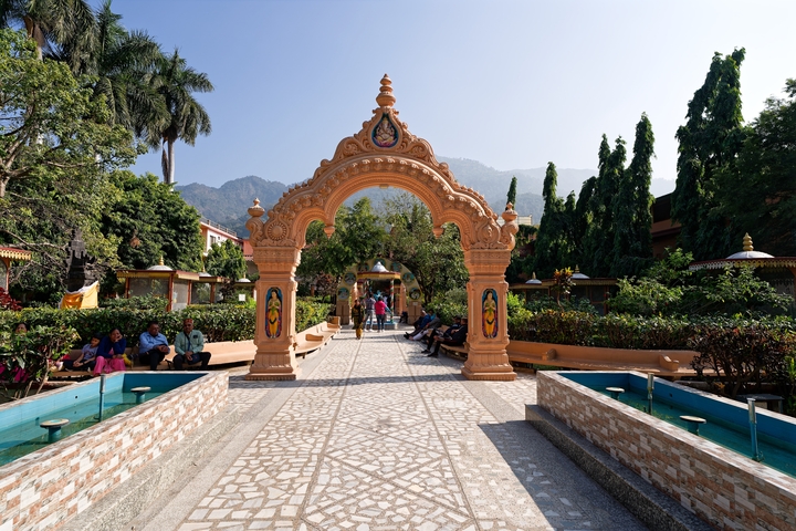 Decorative archway leading to a garden with mountains in the background.