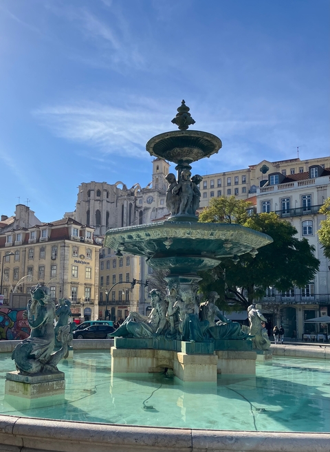       Historic fountain in a square with classical buildings.
  