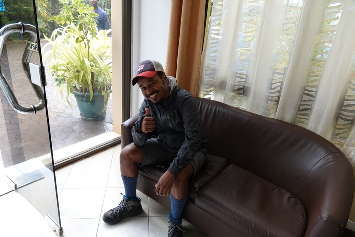       Man sitting on a couch giving a thumbs up.
  
