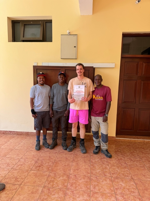       Four men posing with a certificate, standing in front of a wall.
  